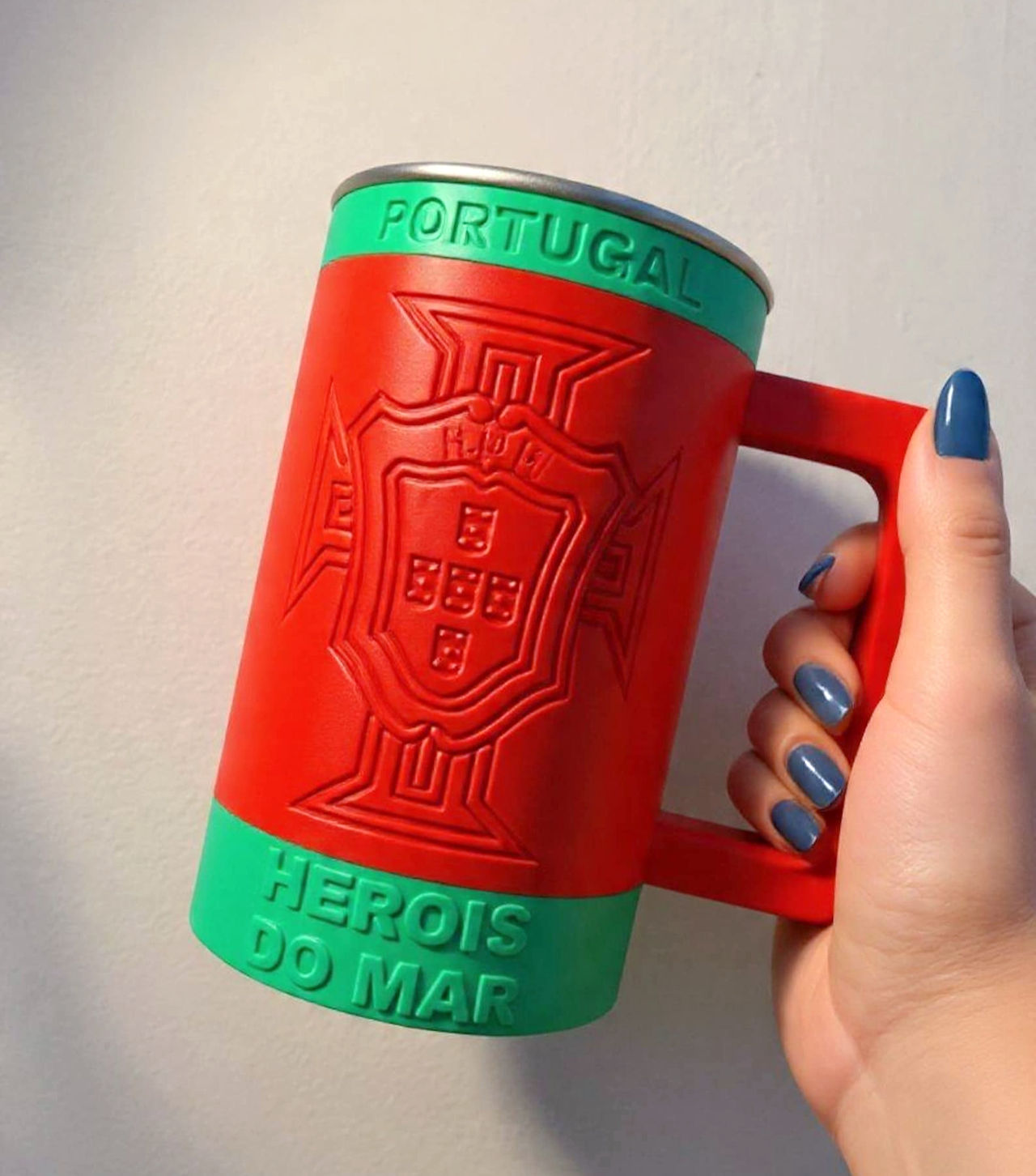 Red and green stainless steel mug that has emblem of portuguese futbol federation and says "Portugal "and "herois do mar" in the green sections at the top and bottom