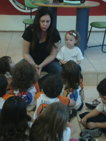 Foto da autora Shirley Souza conversando com um grupo de crianças do maternal.
