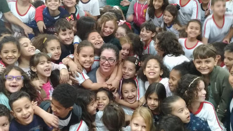 Foto da autora Shirley Souza abraçada por dezenas de crianças.