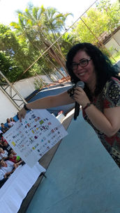Foto da autora Shirley Souza com um cartaz produzido por alunos com um enigma inspirado no livro Um caso muito sujo.