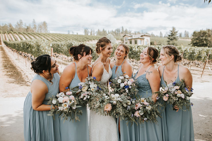 Bride with her bridesmaids, holding fresh flower bouquets.