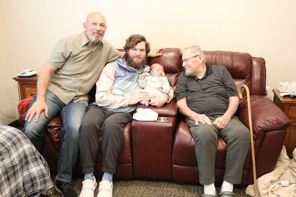 Four generations of men sit together on a couch
