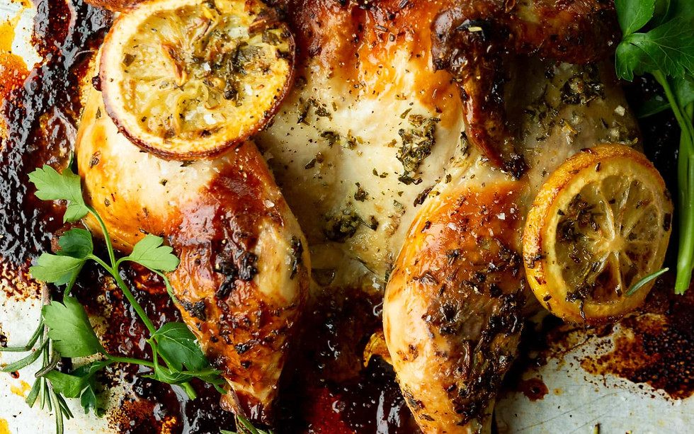 Roasted lemon chicken on a tray with fresh herbs