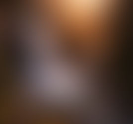 A powerful waterfall plunges from a granite cliff into a rushing river below, golden sunlight illuminating mist and rugged peaks beyond, evoking limitless strength, command, and the force that shapes the living world.