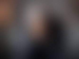 An older man sits alone indoors with his face buried in his hands, his posture heavy with distress and reflection. The softly blurred background and subdued lighting emphasize the emotional weight of regret, loss, and unresolved life choices often explored in discussions of deathbed regrets.