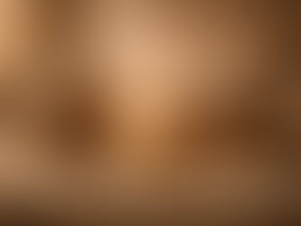 Still life with a serene stone Buddha statue resting on stacked books, a glowing lotus-shaped candle, rolled scrolls, prayer beads, an armillary sphere, a smooth stone, and reading glasses arranged on draped fabric in warm, contemplative light.