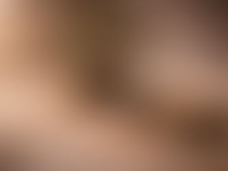 Minimalist still life with a small bonsai tree in a shallow stone bowl on a stone slab, smooth river stones, dried herbs, and a single lit lotus-shaped candle, set against soft fabric in warm, tranquil light.