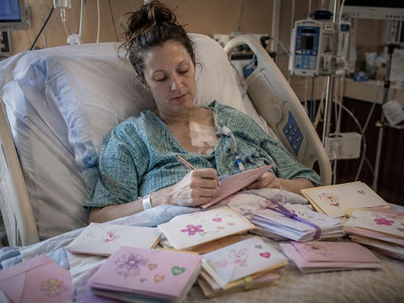 A woman in a hospital gown sits propped up in a hospital bed, surrounded by medical monitors, IV lines, and treatment equipment that indicate serious illness. Resting across her lap and bedside table are dozens of handwritten letters and decorated envelopes prepared for loved ones. Some envelopes feature hand-drawn flowers, hearts, and colorful stickers, while others are bundled into small stacks tied neatly with ribbons. With a pen in hand, she works on another letter, adding to the collection of messages intended for future birthdays, milestones, and special occasions. The contrast between the clinical hospital environment and the care poured into each envelope creates a deeply moving scene of love, preparation, and connection that will continue long after she is gone.