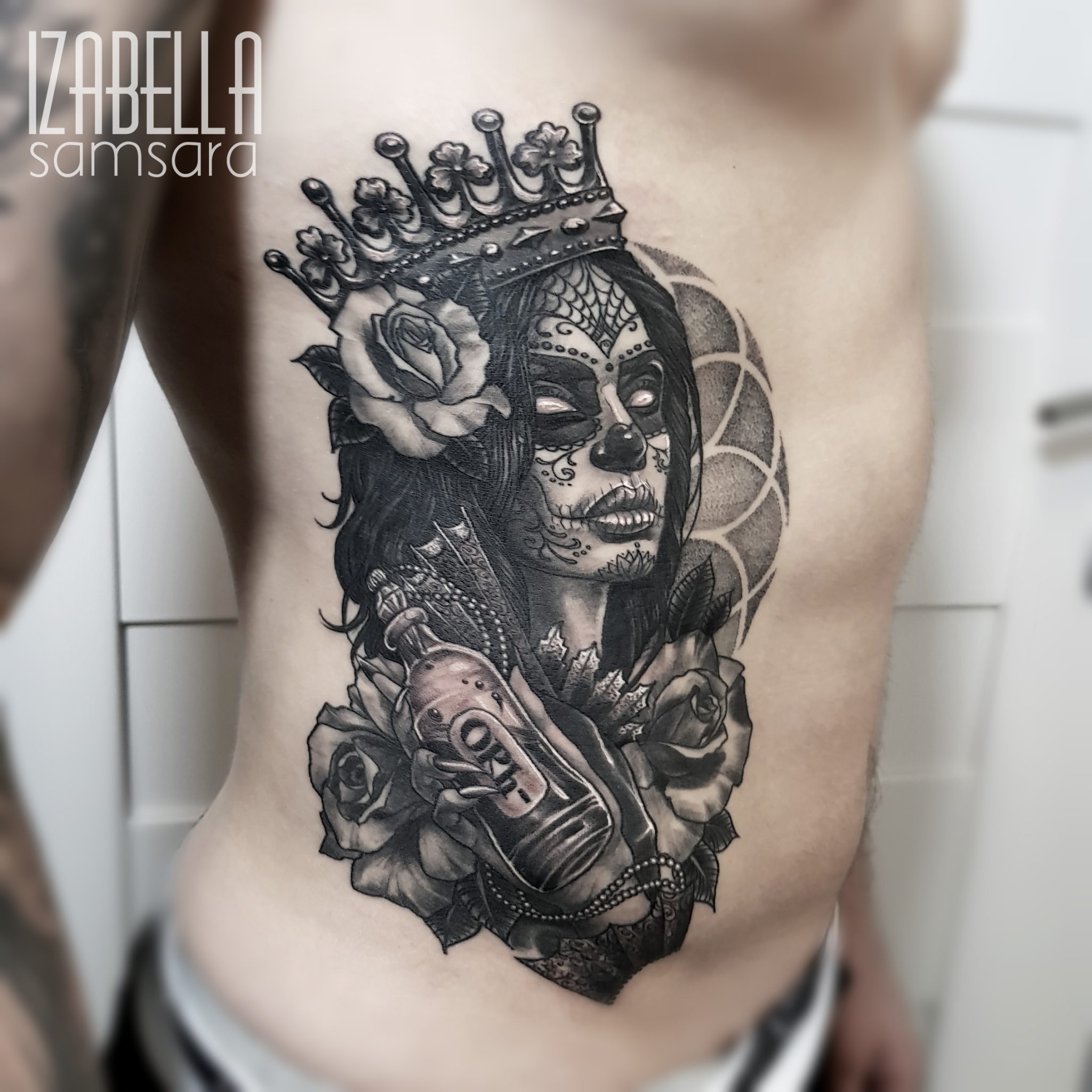 A detailed black and grey tattoo featuring a sugar skull woman with a crown, adorned with roses. The design includes a decorative skull, flowers, and a bottle in her hand, set against a patterned background. Perfect for showcasing Day of the Dead themes and Gothic art.