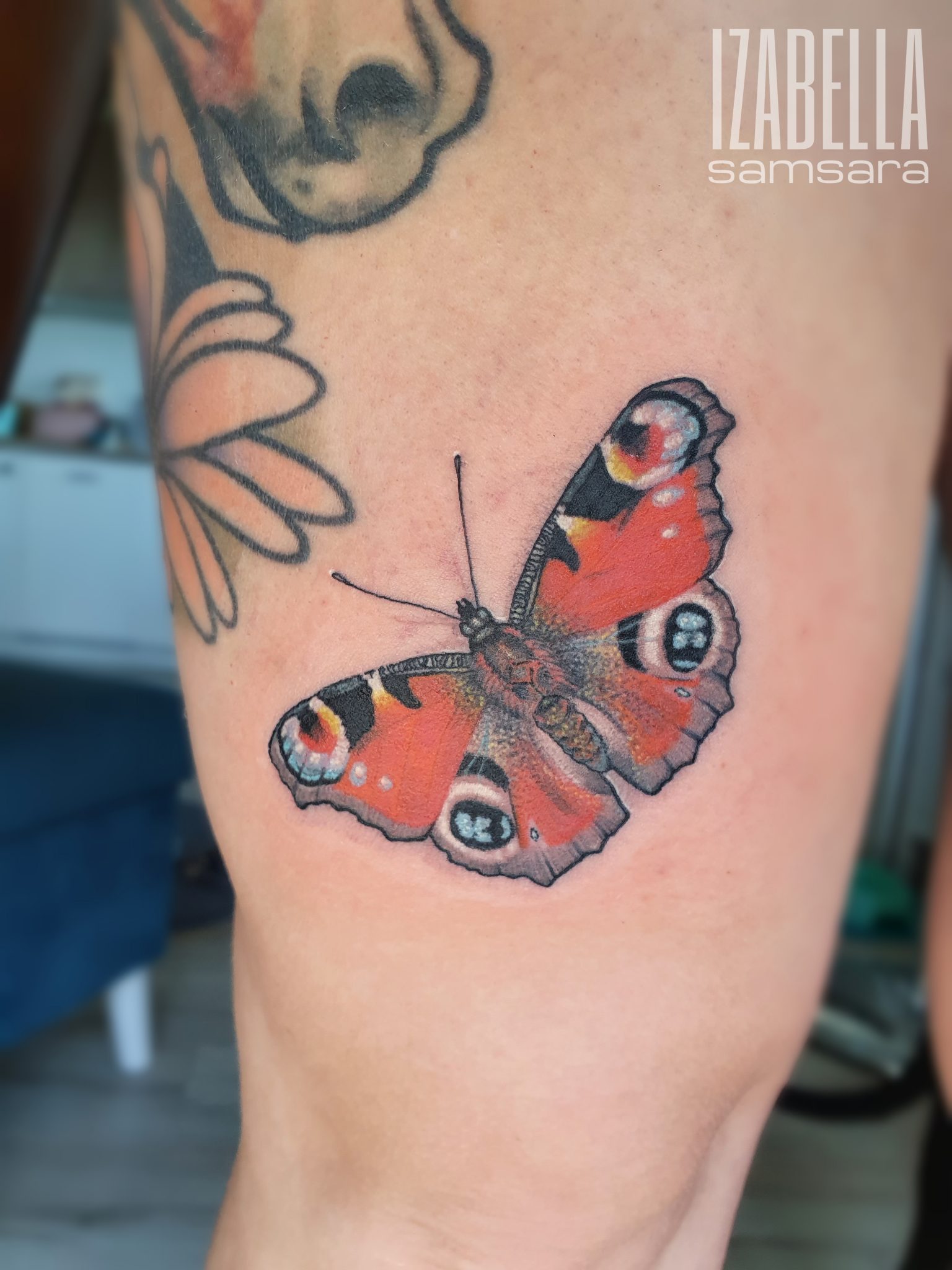 Realistic tattoo of a vibrant red butterfly with black and yellow accents, featuring intricate details and clear patterns. The butterfly is positioned prominently on the skin, showcasing its colorful wings in a natural pose.
