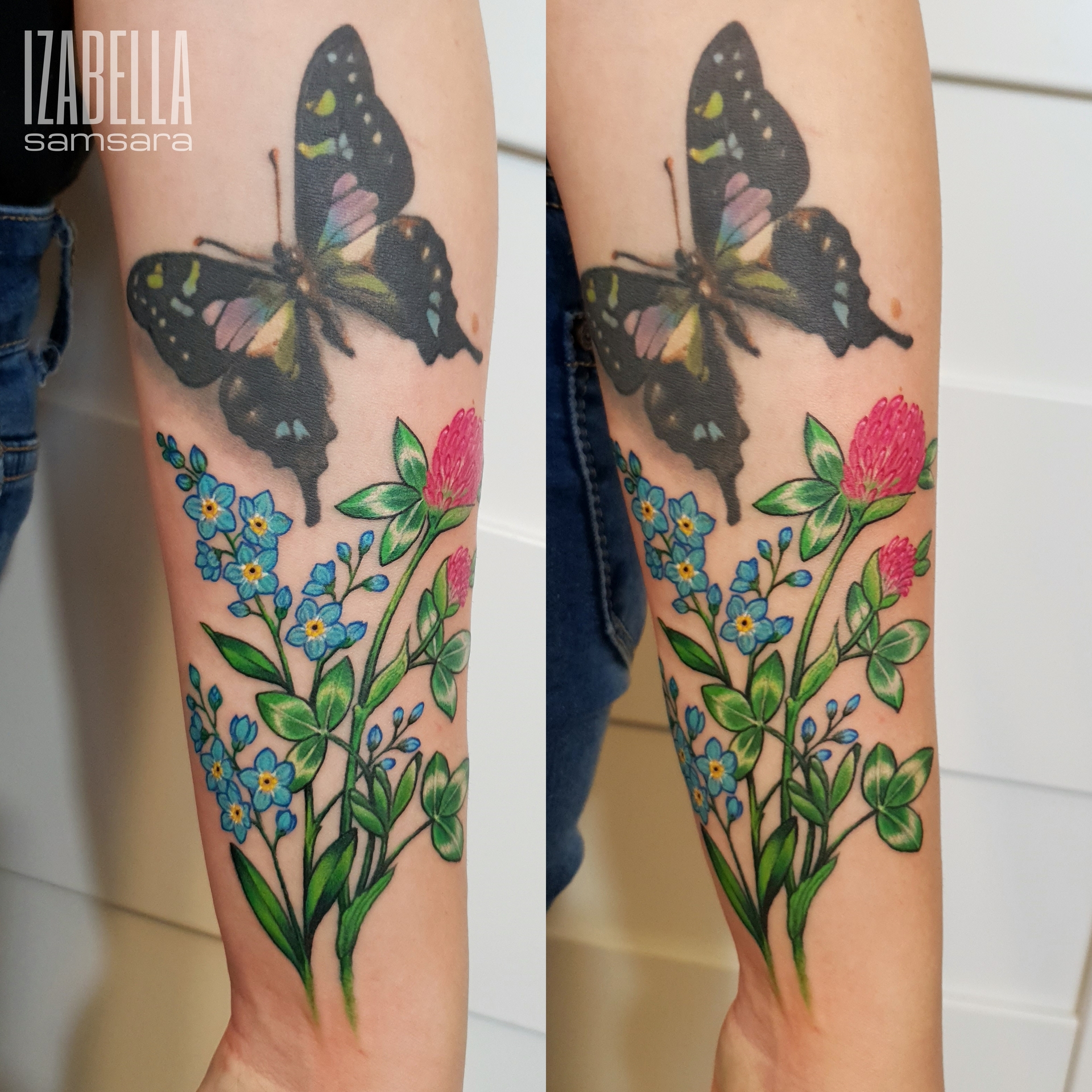 A vibrant tattoo featuring a large black and green butterfly with detailed wings, surrounded by colorful flowers and foliage. The design includes delicate blue forget-me-nots and pink clover blooms, all rendered in a realistic style with intricate shading and vivid colors, showcasing the beauty of nature.