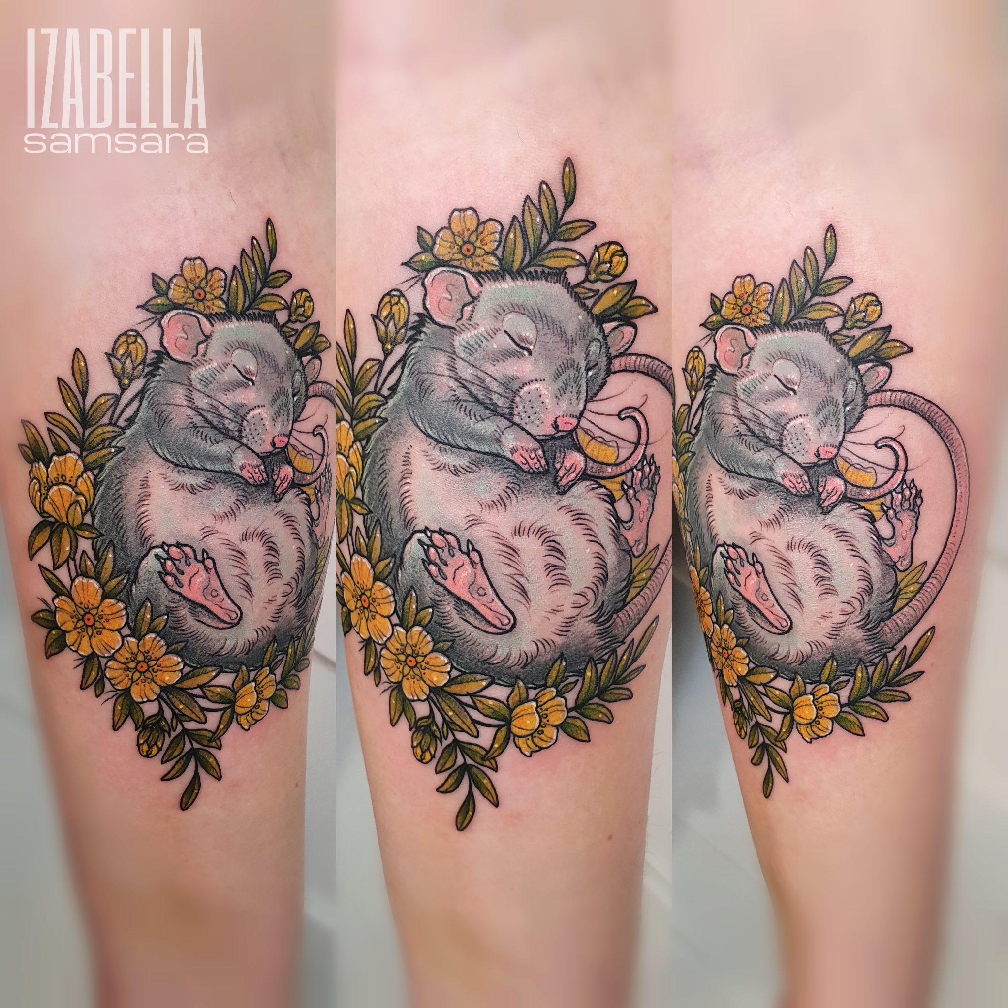 A detailed color tattoo of a sleeping gray rat surrounded by vibrant yellow flowers and green leaves. The rat is curled up, with its eyes closed and a content expression, showcasing its pink paws and long tail. The design features intricate linework and shading, emphasizing the softness of the rat's fur and the natural beauty of the floral elements.