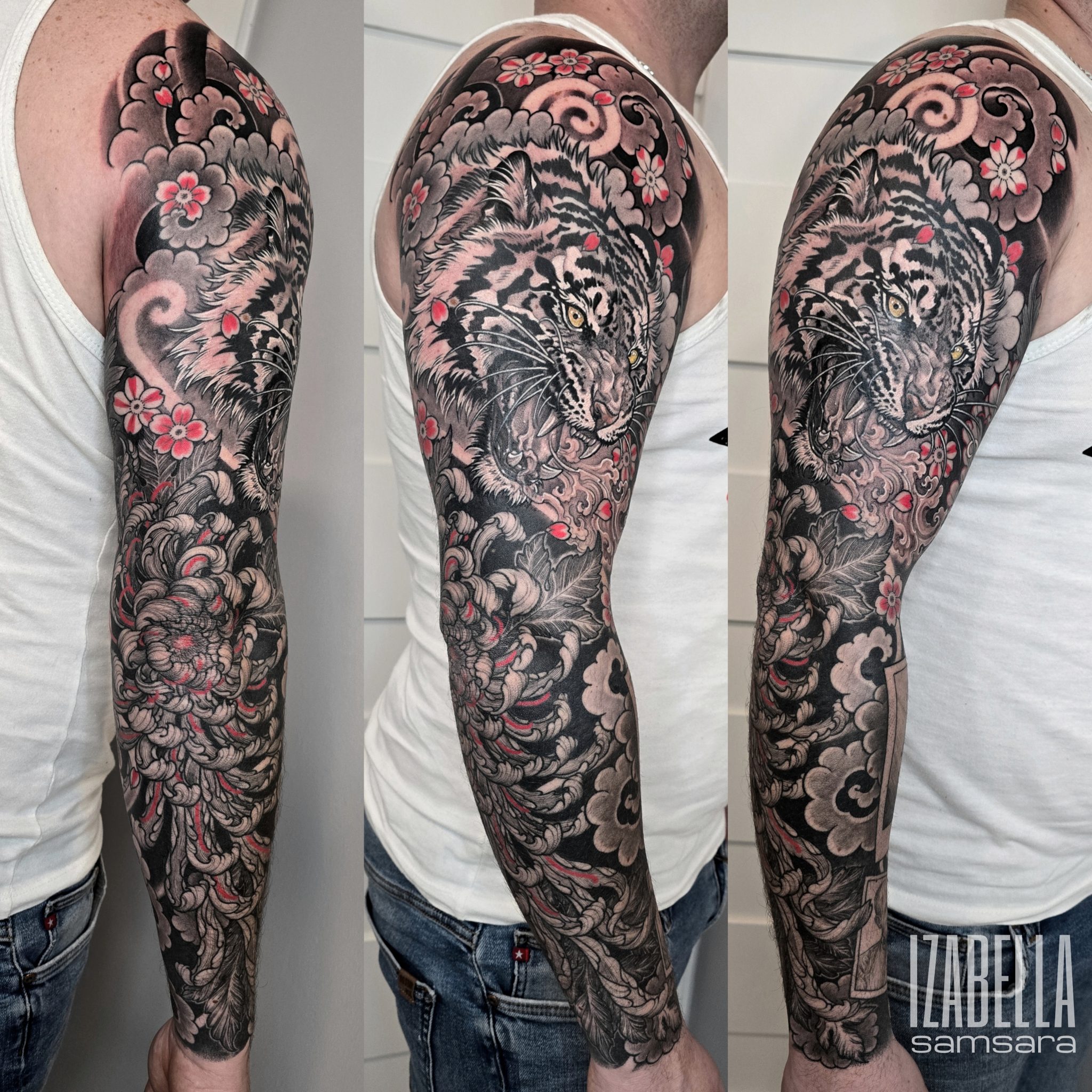Detailed black and gray tattoo depicting a roaring tiger surrounded by floral elements and swirling patterns. The tiger features striking yellow eyes and intense facial markings, while the flowers are adorned with hints of red, creating a dynamic and vibrant contrast against the dark ink. This full sleeve tattoo showcases intricate shading and line work, blending realism with stylized elements.