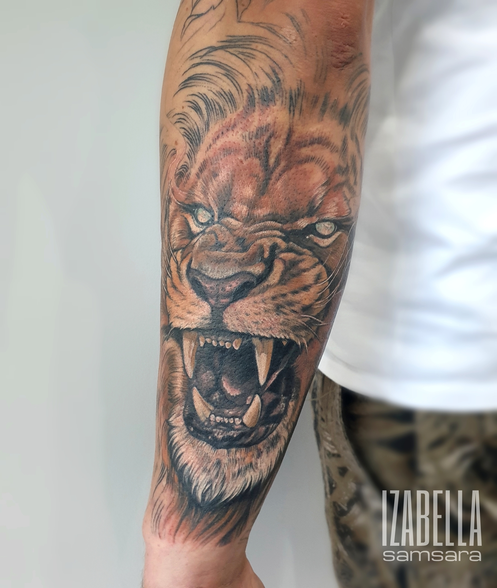 Realistic lion tattoo on forearm featuring fierce expression, detailed fur, sharp teeth, and intense eyes, showcasing vibrant colors and intricate shading, perfect for animal and wildlife tattoo enthusiasts.