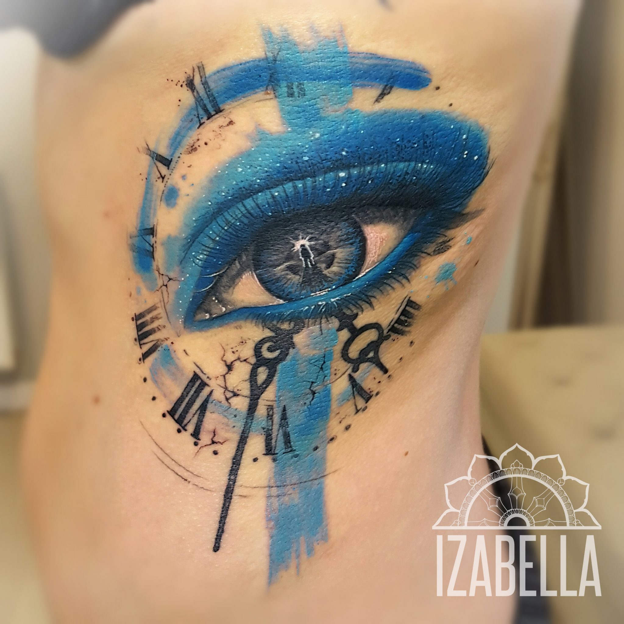 A stunning tattoo featuring a beautifully detailed blue eye surrounded by clock elements, showcasing intricate black clock hands and Roman numerals, with a watercolor effect in blue tones and splashes. This design emphasizes themes of time and perception, making it a captivating piece for tattoo enthusiasts.