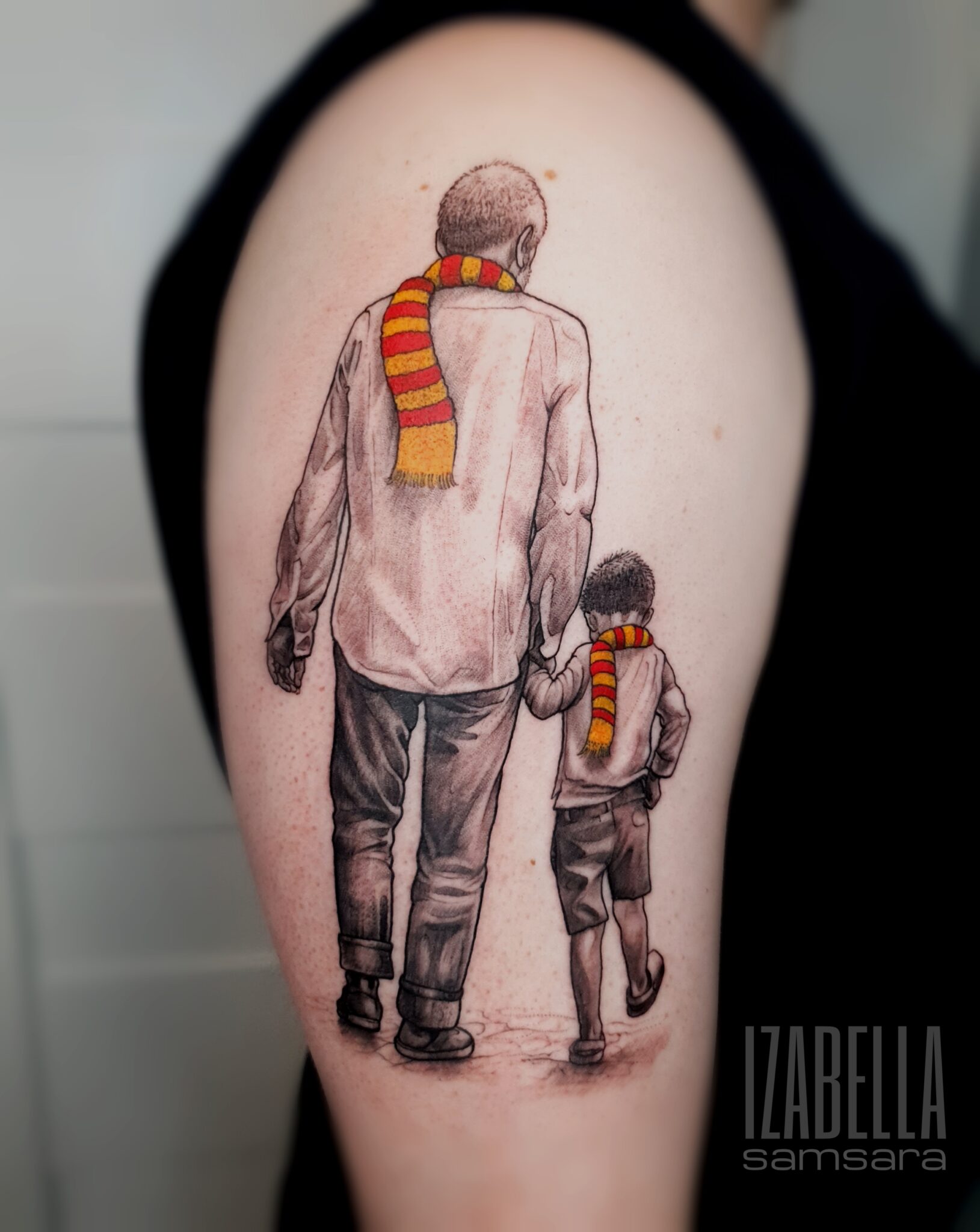 A heartwarming tattoo depicting a man and a boy walking together hand-in-hand. The man is shown from the back, wearing a white shirt and gray pants, while the boy, slightly shorter, wears a blue shirt and shorts. Both are adorned with vibrant red and yellow striped scarves. The scene conveys a sense of warmth and connection, perfect for family-themed tattoo searches.