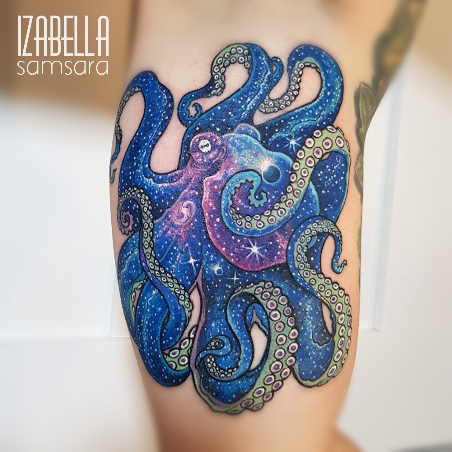 A vibrant and colorful tattoo of an octopus surrounded by a cosmic theme, featuring galaxies, stars, and a mix of deep blues and purples. The octopus has fluid, swirling tentacles with intricate details, showcasing bright green suckers and a whimsical expression, set against a starry background that creates a captivating celestial effect.