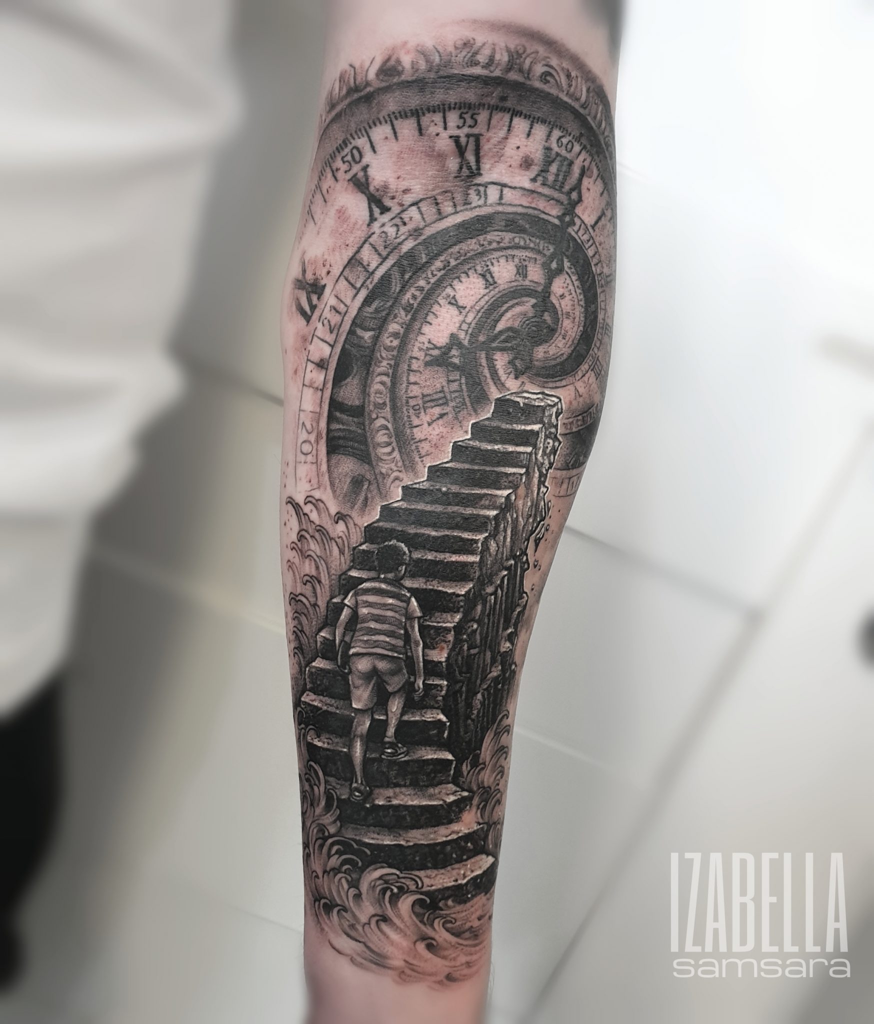 A detailed black and gray tattoo depicting a young boy walking up a staircase that appears to rise from turbulent waves. In the background, there's a vintage clock with intricate gears, suggesting themes of time and journey. The design is realistic and filled with shading, emphasizing depth and movement.
