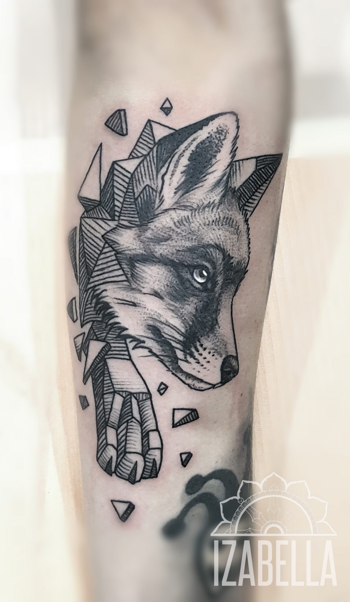 A detailed black and white tattoo of a fox's head, emerging from a geometric shattered design. The fox features expressive eyes and intricate fur detailing, surrounded by angular fragments and a dynamic composition that conveys movement and depth.