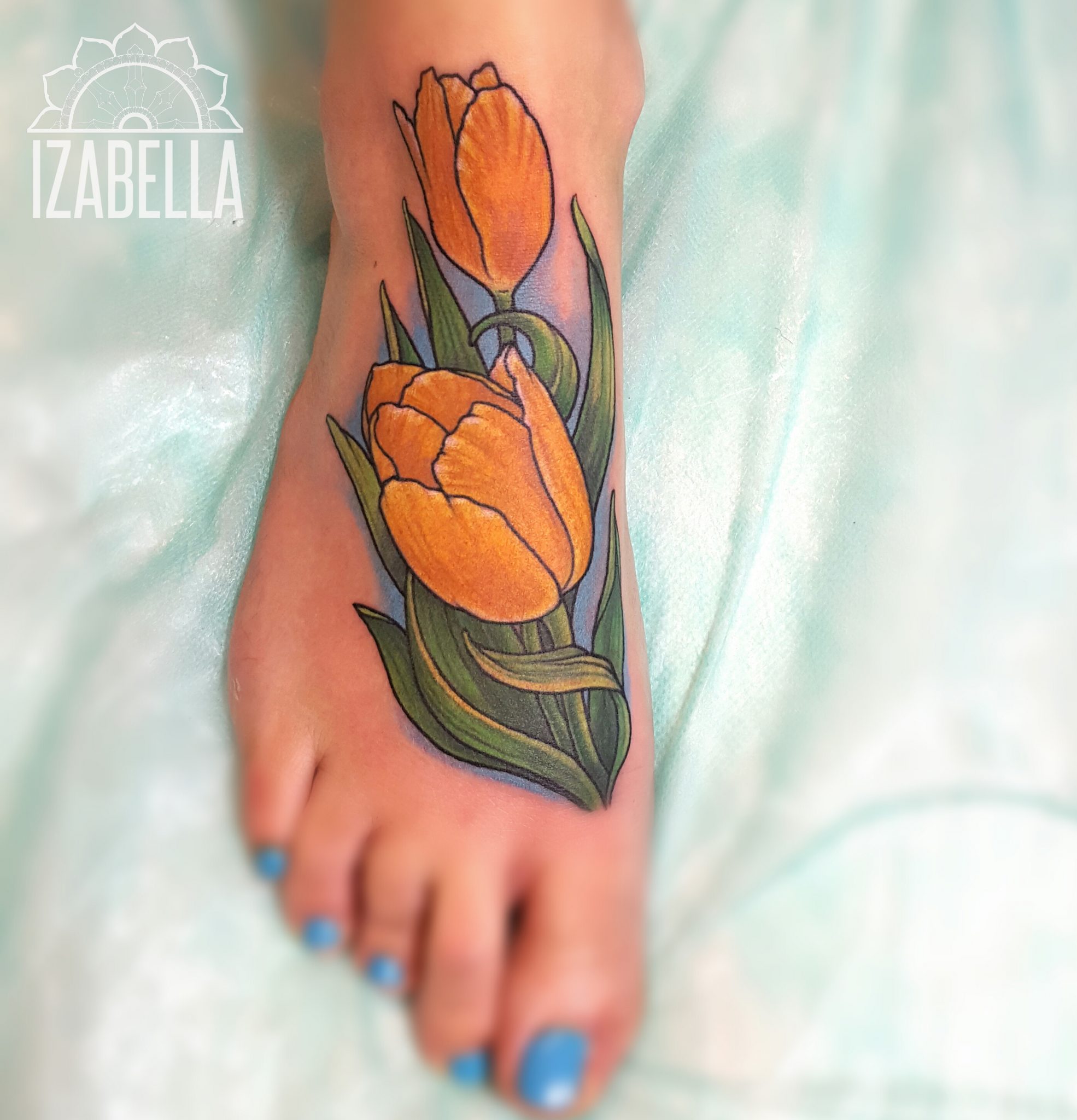 A vibrant tattoo of two orange tulips with green leaves, positioned on the foot. The tulips are intricately designed, showcasing detailed petals and realistic shading, set against a soft background.