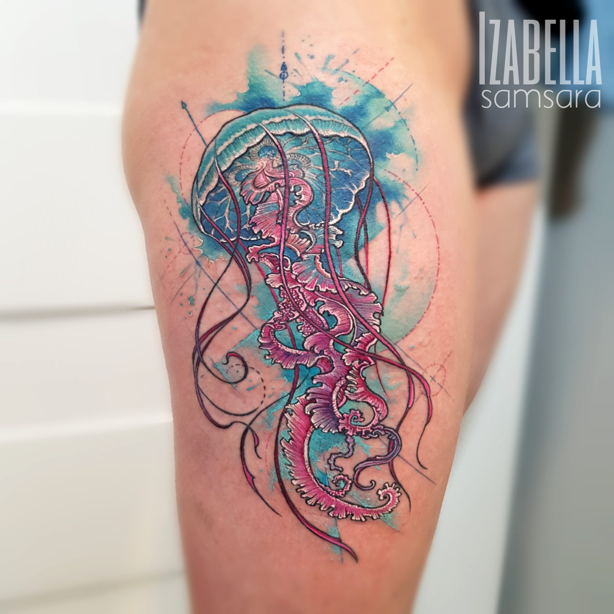 A vibrant jellyfish tattoo featuring intricate details in shades of blue and pink. The jellyfish has long, flowing tentacles and is surrounded by abstract watercolor splashes that enhance its ethereal look. This tattoo showcases a modern artistic style with a blend of realism and creativity on the thigh.