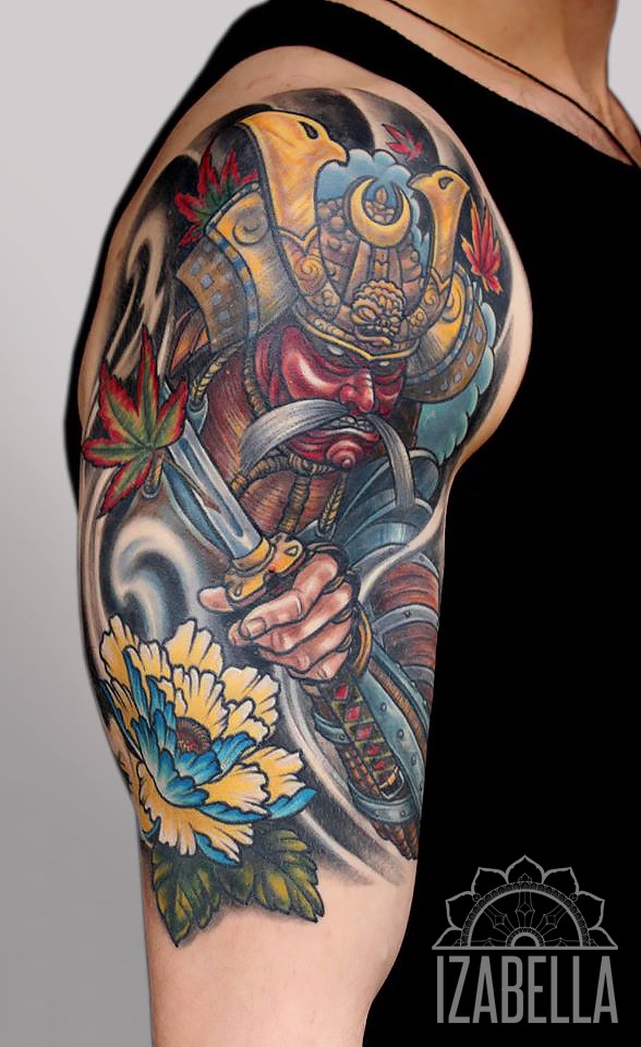 A colorful tattoo depicting a samurai warrior holding a sword, adorned with intricate details. The samurai has a red face and ornate armor with gold elements, surrounded by vibrant leaves. The design also features a large blue and yellow flower at the bottom, with swirling elements in the background, showcasing a blend of traditional Japanese art style.