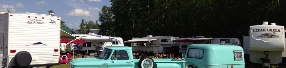 Teal vintage truck and camper with more campers in the background at Clymont