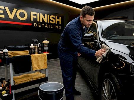 Detailer working on luxury sedan in studio