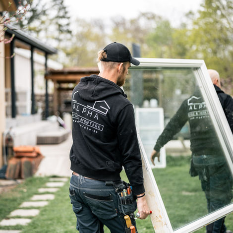 Två fönstermontörer bär in nytt fönster inför installation i villa