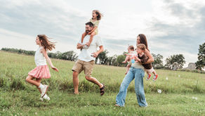 Playful family walking in a grassy field during a family photography session in Frederick, Maryland.