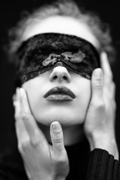 a black and white photo of a woman wearing a lace blindfold