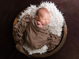 Newborn baby in wooden bowl