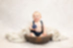 Boy sitting in a wooden bowl holding a toy