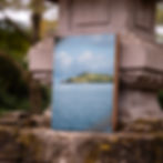 Holzbild mit grüner Insel und ruhigem Meer angelehnt am Steinschrein als Produktmockup