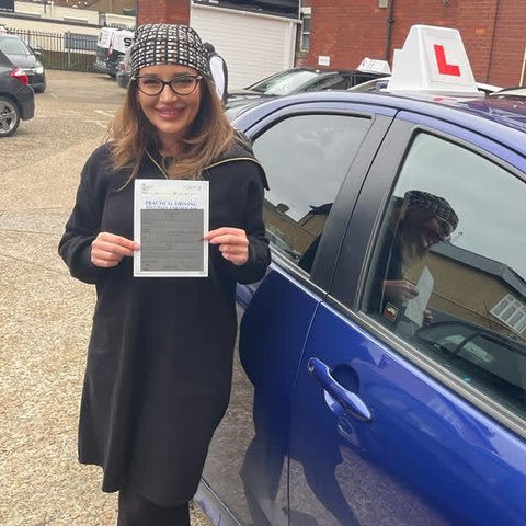 A woman with a bandana next to a blue car