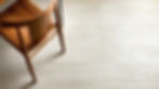 Wooden chair on light textured tile floor, set against a simple, minimalist background. Calm atmosphere with earthy tones.