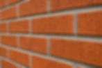 Concave mortar joints on a red thin brick wall with recessed curved grooves