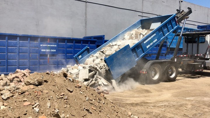 High angle view of a dumpster rental truck delivering a small dumpster