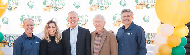 CSG exec team smiling for photo in front of CSG banner