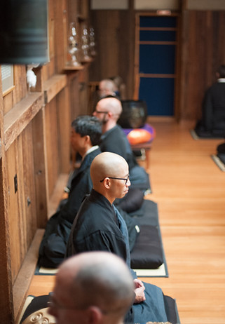 five people in black robes meditating in Zendo