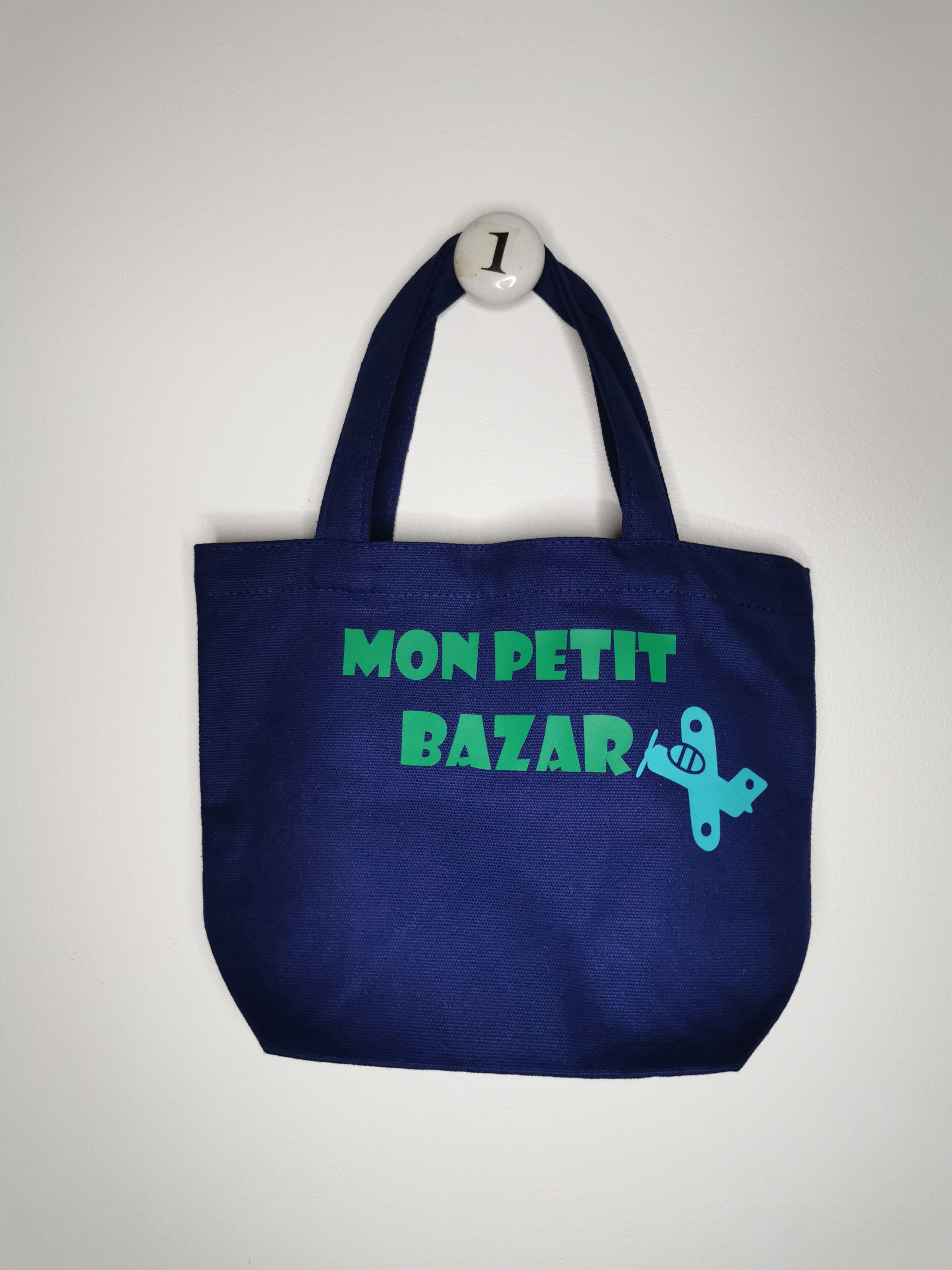 tote bag enfant, bleu inscription verte "mon petit bazar" avec un avion