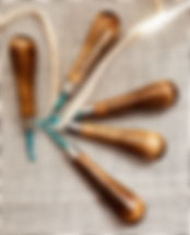 Primitive rug hooks displayed on a piece of primitive linen and a wool strip_edited.jpg