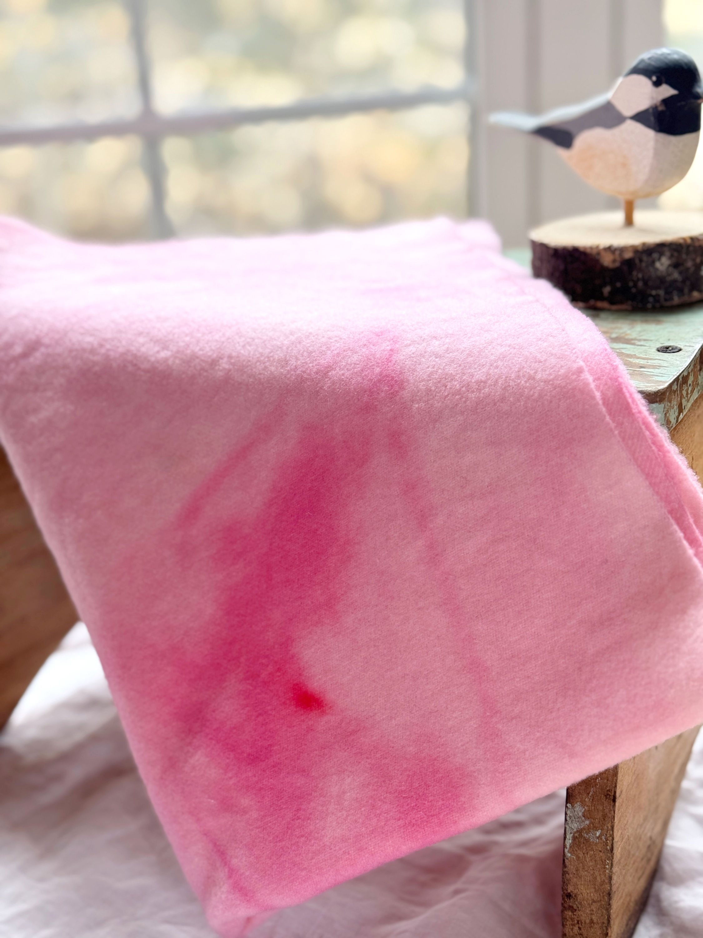 hand dyed pink wool fat quarter draped on a stool with a bird