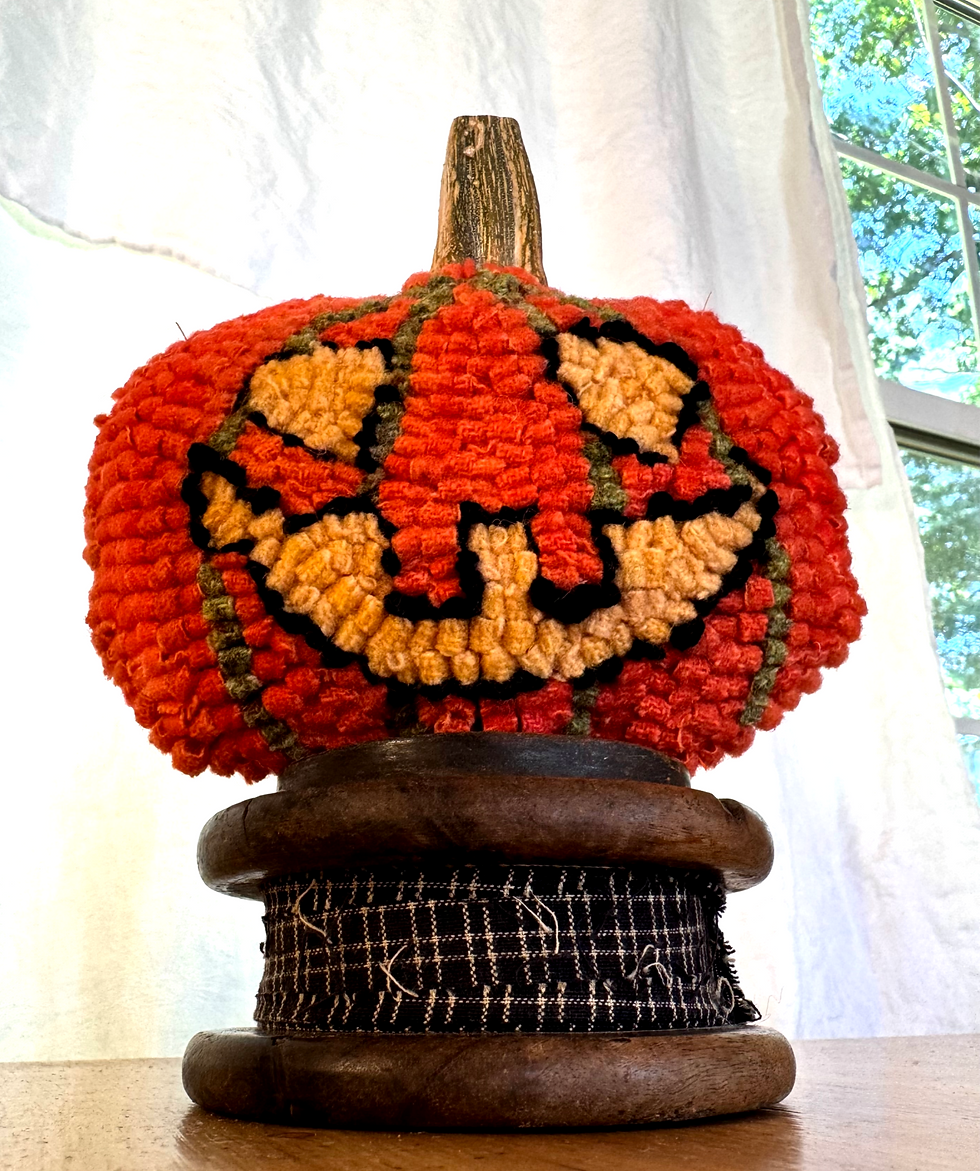 handmade hooked wool pumpkin on wooden spool