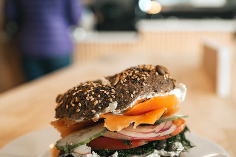 Lox bagel sandwich with red onion, schmear, dill, and more on a pumperickel bagel