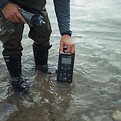 waders in saltwater with arm holding a scientific measuring instrument.jpg