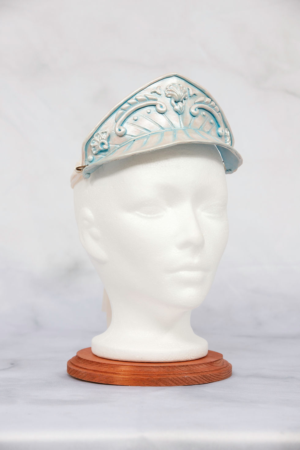 Thumbnail: White mannequin head wearing a detailed, ornate silver and blue crown.