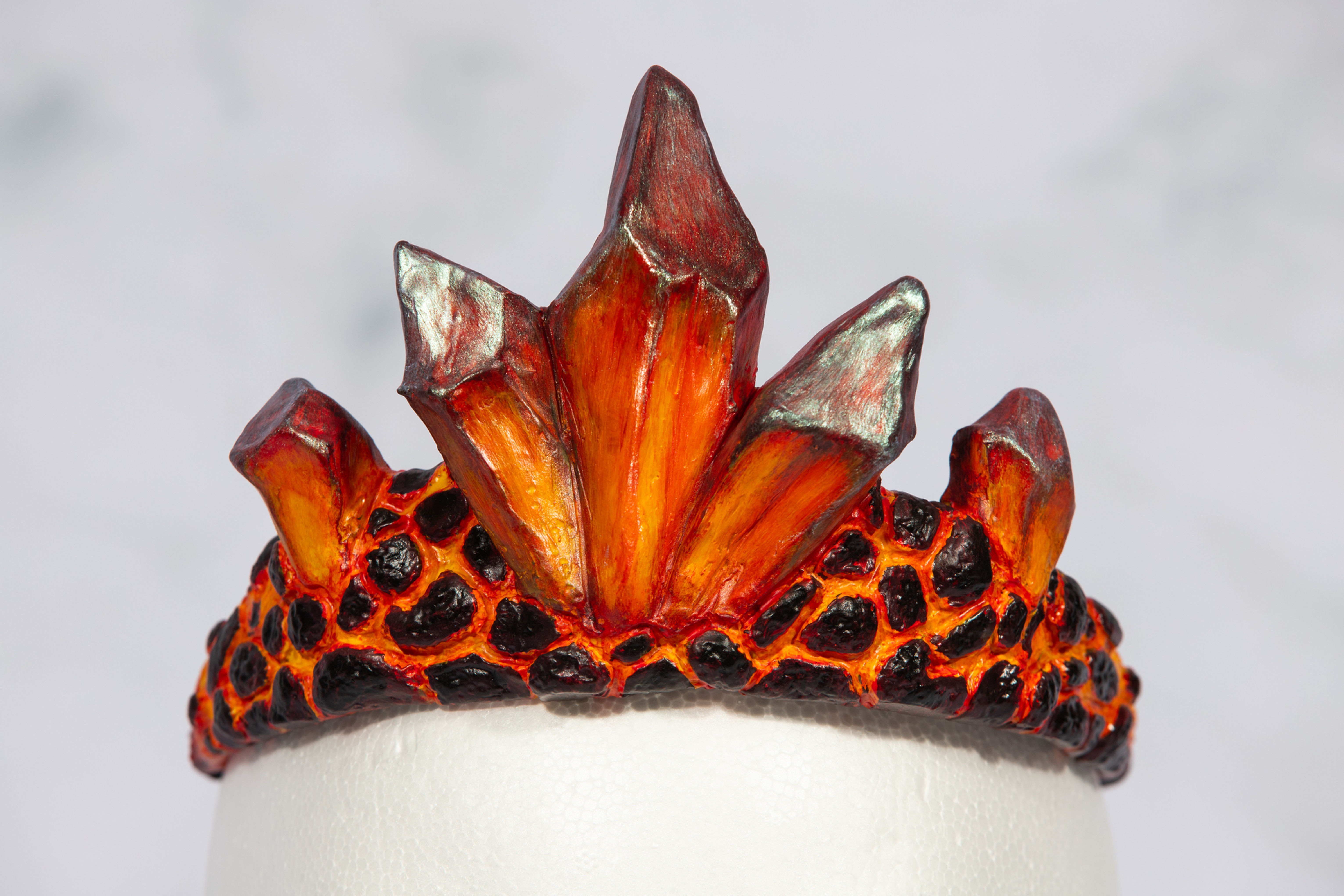 Volcanic crown with orange and black detailing on a marble background.
