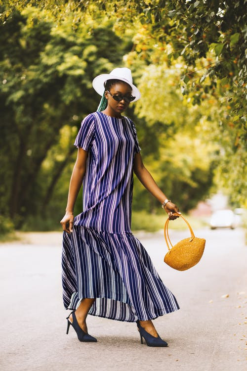 Woman in stripe dress walking with a basket bag in her hand