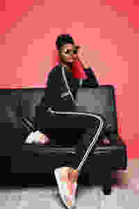 Woman sitting down in a chair wearing a track pants suit